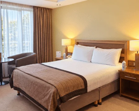 Modern hotel room with cosy seating and a large window view.