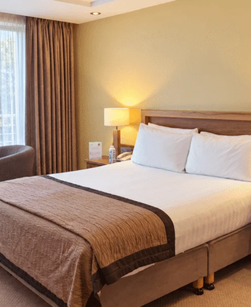 Modern hotel room with cosy seating and a large window view.