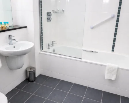 Modern hotel bathroom with bathtub, sink, and complimentary toiletries.