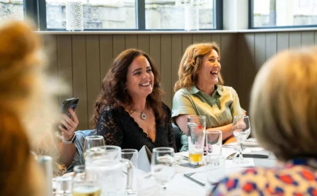 A joyful group dining in a sunlit restaurant, sharing laughter and conversation.