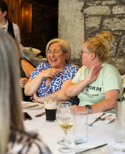 A cheerful group dining at a rustic stone restaurant, enjoying drinks and laughter.