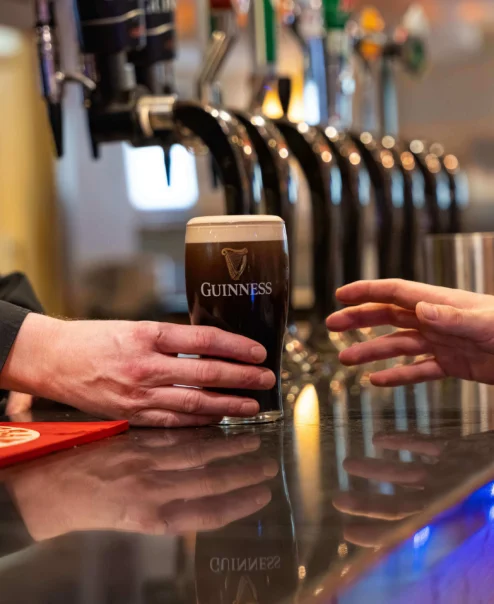 Bartender serving a pint of Guinness to a guest at a cosy hotel bar.