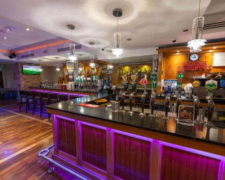Modern hotel bar with vibrant lighting and cosy seating for families and couples.