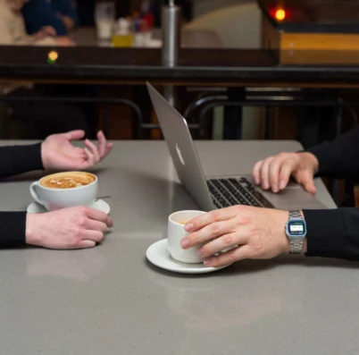 Couple enjoying coffee and using a laptop in a cosy café setting.