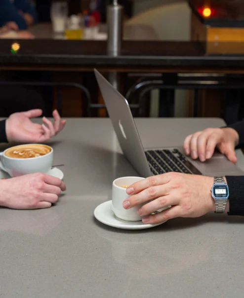 Couple enjoying coffee and using a laptop in a cosy café setting.