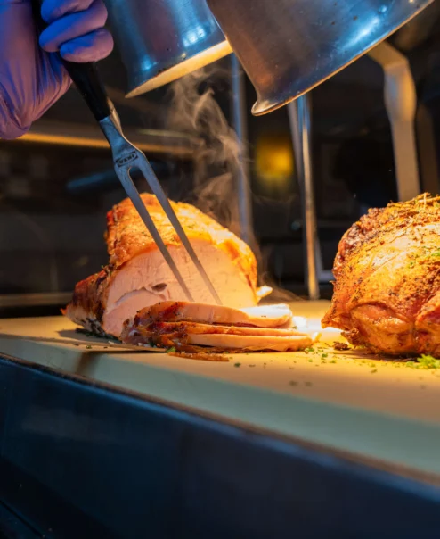 A chef carves a succulent roast for a warm, inviting buffet setting.