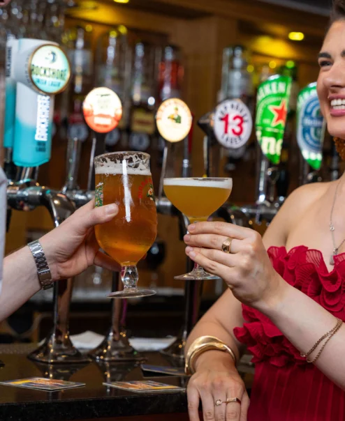 A couple toasting drinks at a cosy hotel bar.