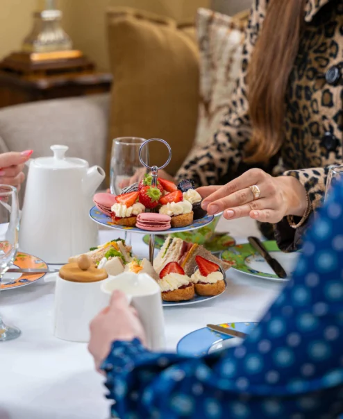 Family enjoying afternoon tea with pastries in a cosy, elegant setting. Warm atmosphere.