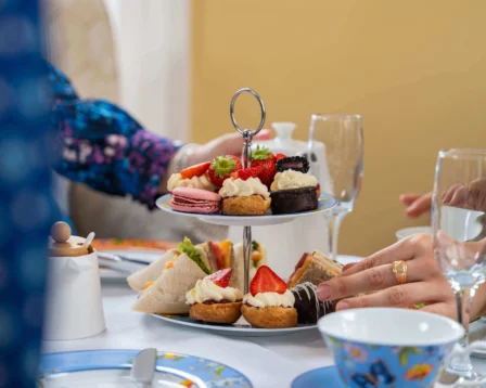 Family enjoying afternoon tea with pastries and desserts in a cosy setting.