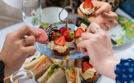 Family enjoying afternoon tea with sandwiches and pastries in a cosy setting.