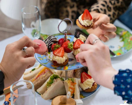 Family enjoying afternoon tea with sandwiches and pastries in a cosy setting.