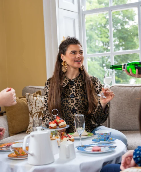 Family enjoying afternoon tea in cosy hotel lounge, sharing conversation and laughter.