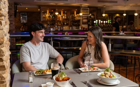 Couple enjoying dinner at a cosy restaurant with stylish interior lighting.