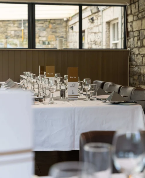 Elegant dining setup in rustic restaurant with stone walls and natural light.