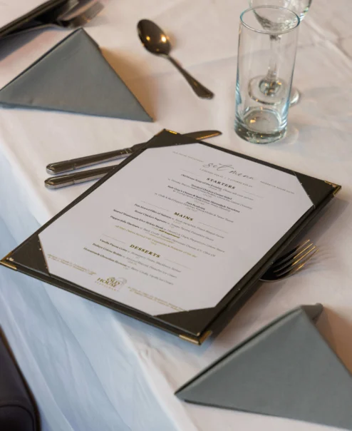 Elegant table setting with menus at a hotel restaurant.