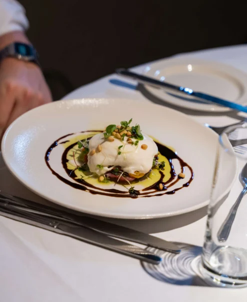 Elegant dining setting with gourmet plated dish, awaiting guest in hospitality environment.