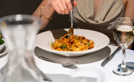 Family enjoying a gourmet pasta meal in a cosy, elegant restaurant setting.