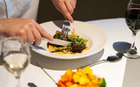 Couple dining on gourmet steak with wine in a cosy hotel restaurant.