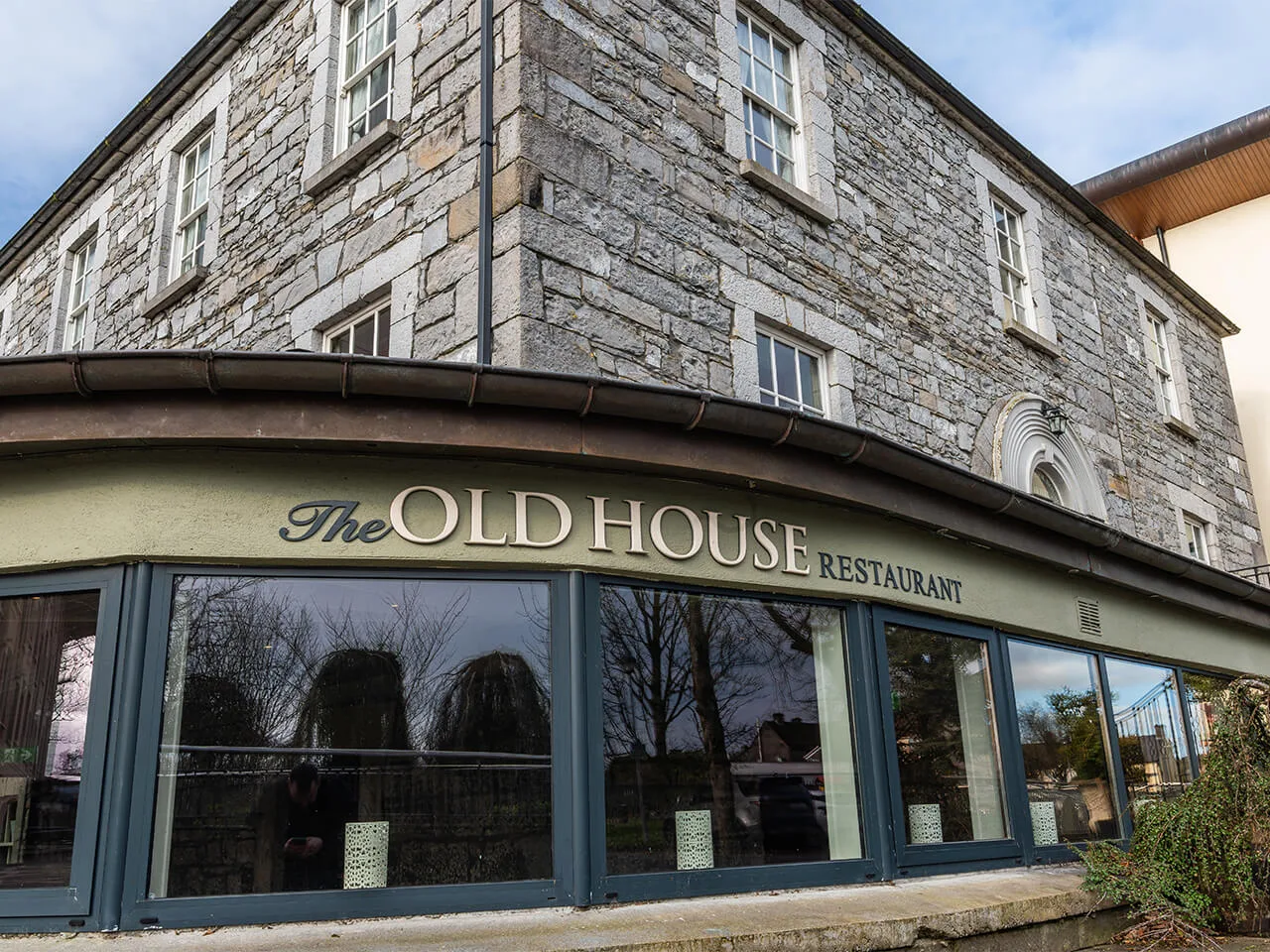 Historic stone restaurant with large windows, "The Old House" sign visible.