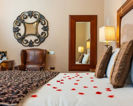 Luxurious hotel room with a cosy bed and rose petals.