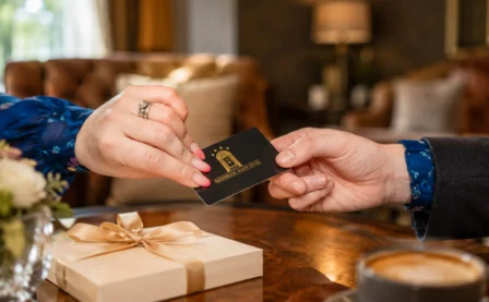 A couple exchanges a gift card in a cosy hotel lounge with warm lighting.