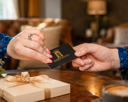 A couple exchanges a gift card in a cosy hotel lounge with warm lighting.