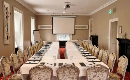 Elegant conference room setup in a hotel with plush chairs and projector screen.