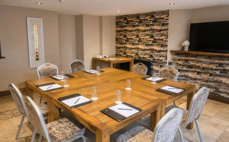 Cosy hotel meeting room with a wooden table, comfy chairs, and a welcoming atmosphere.