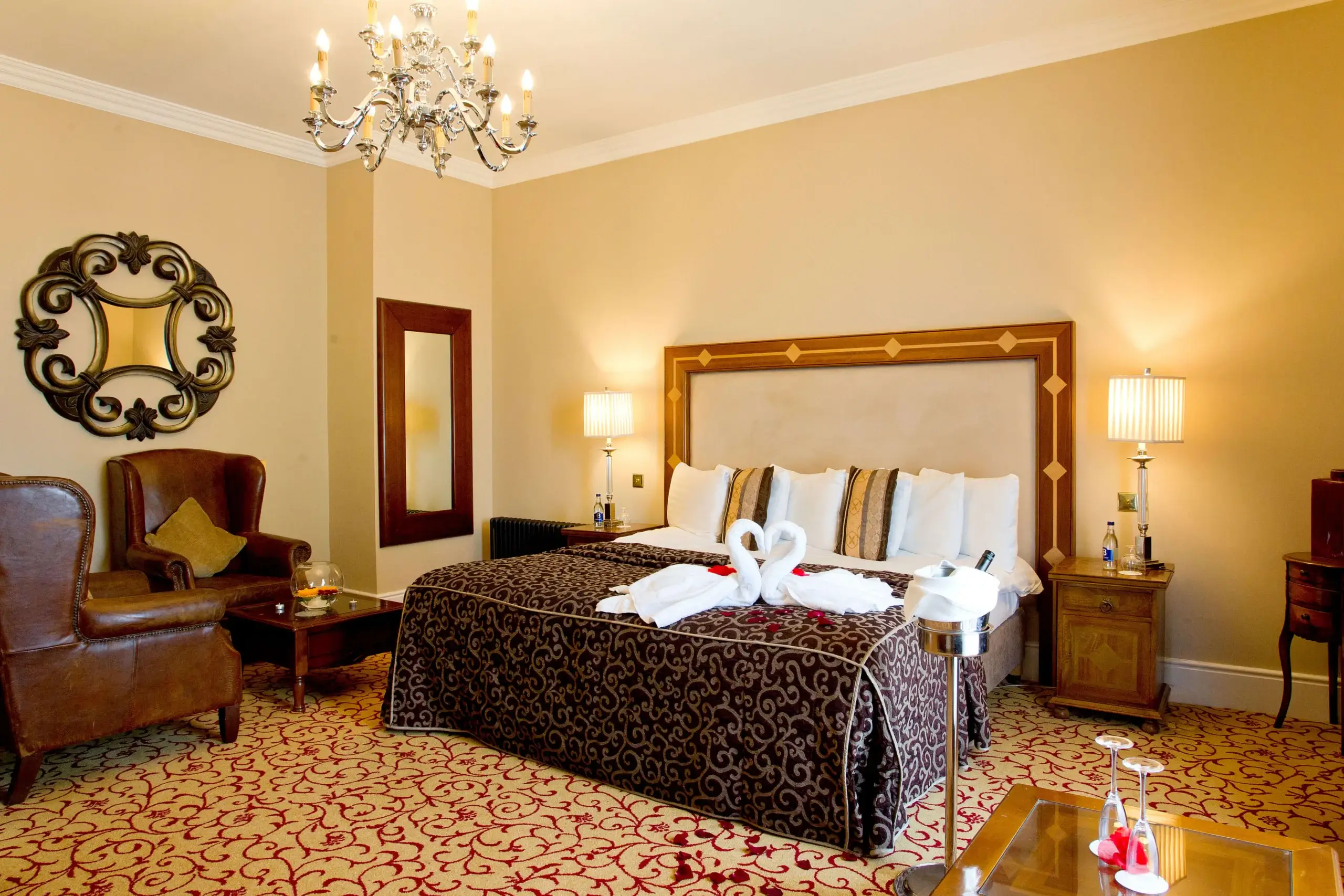 Elegant hotel room with swan towels on a king-size bed, ambient lighting, and vintage decor.