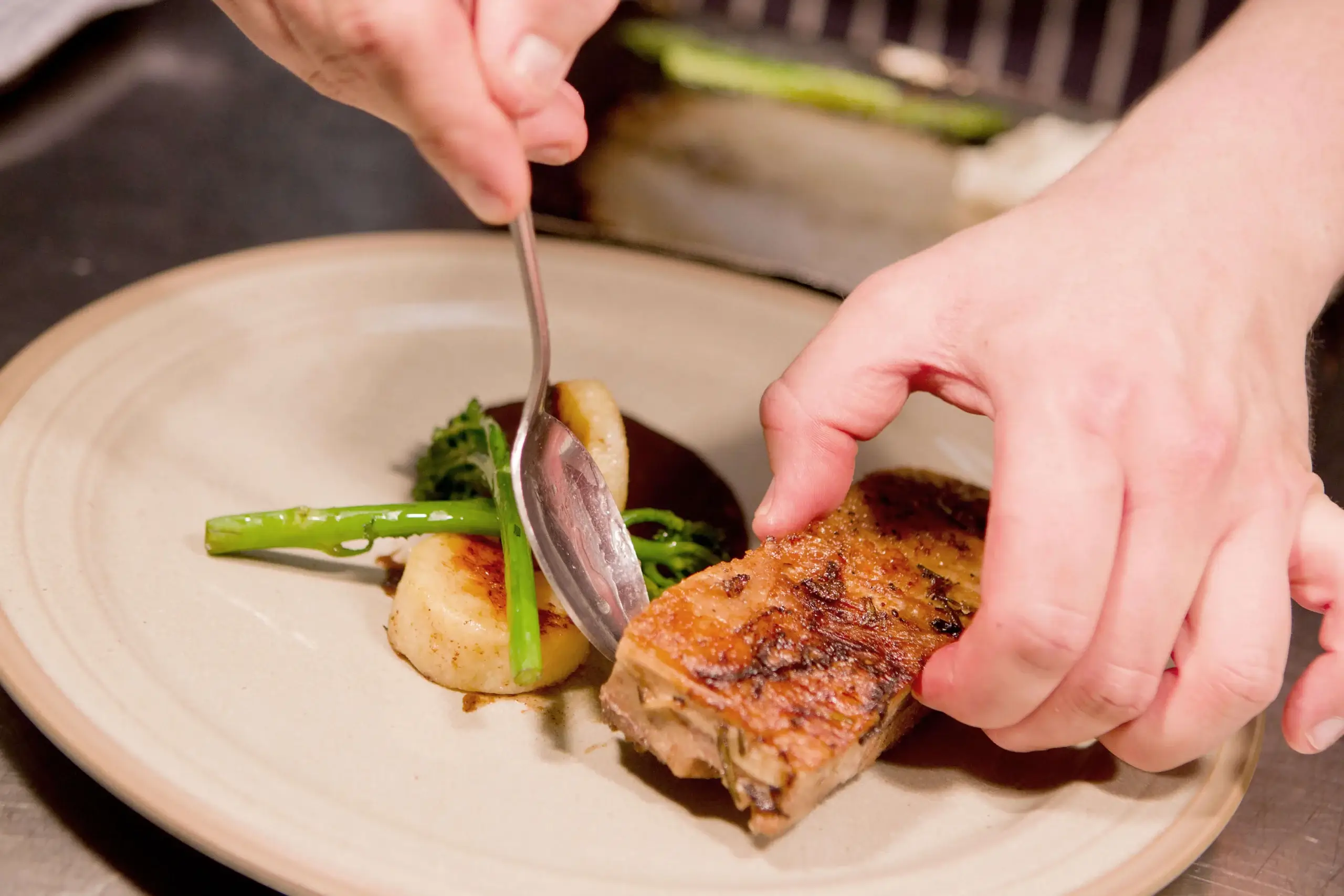 Chef elegantly plating gourmet dish in a warm restaurant setting.