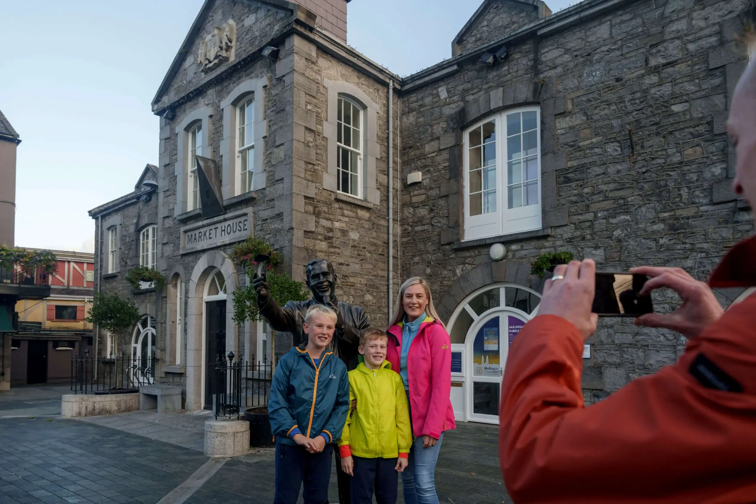Family posing for a photo in front of historic Market House, a stone building with arched windows.