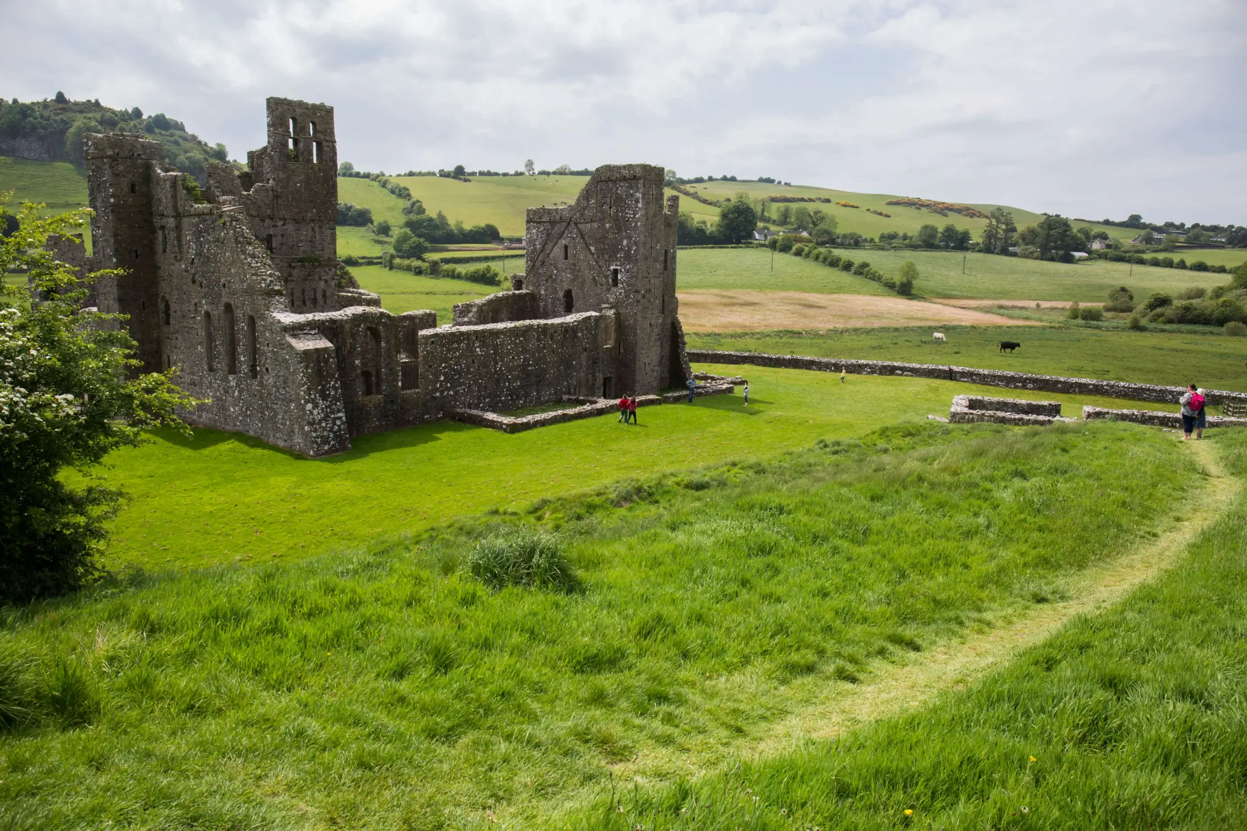 Family exploring historic ruins in lush countryside.