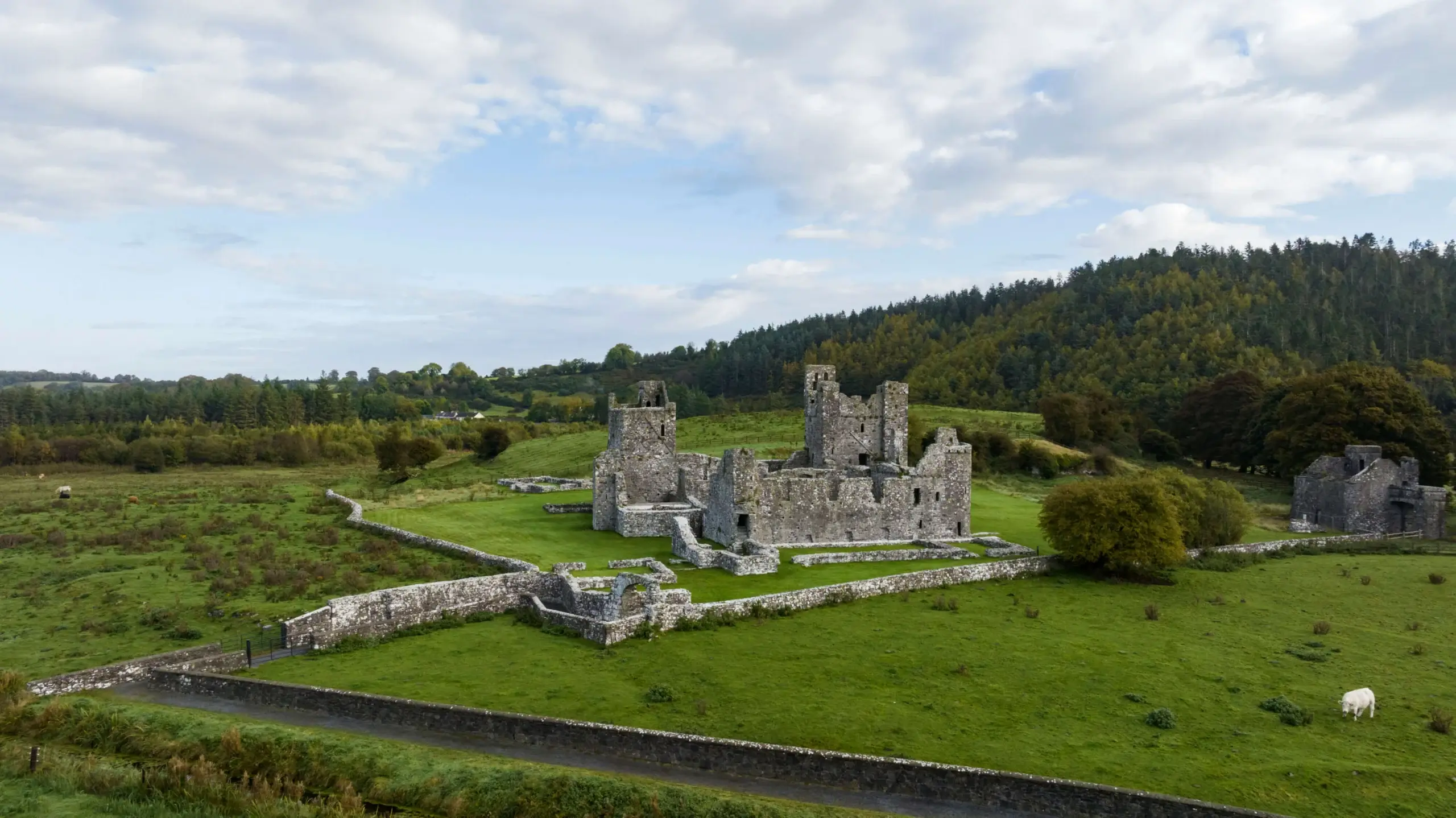 Family exploring historic castle ruins surrounded by lush green countryside.