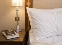 Cosy hotel room with a plush bed, bedside lamp, and books.
