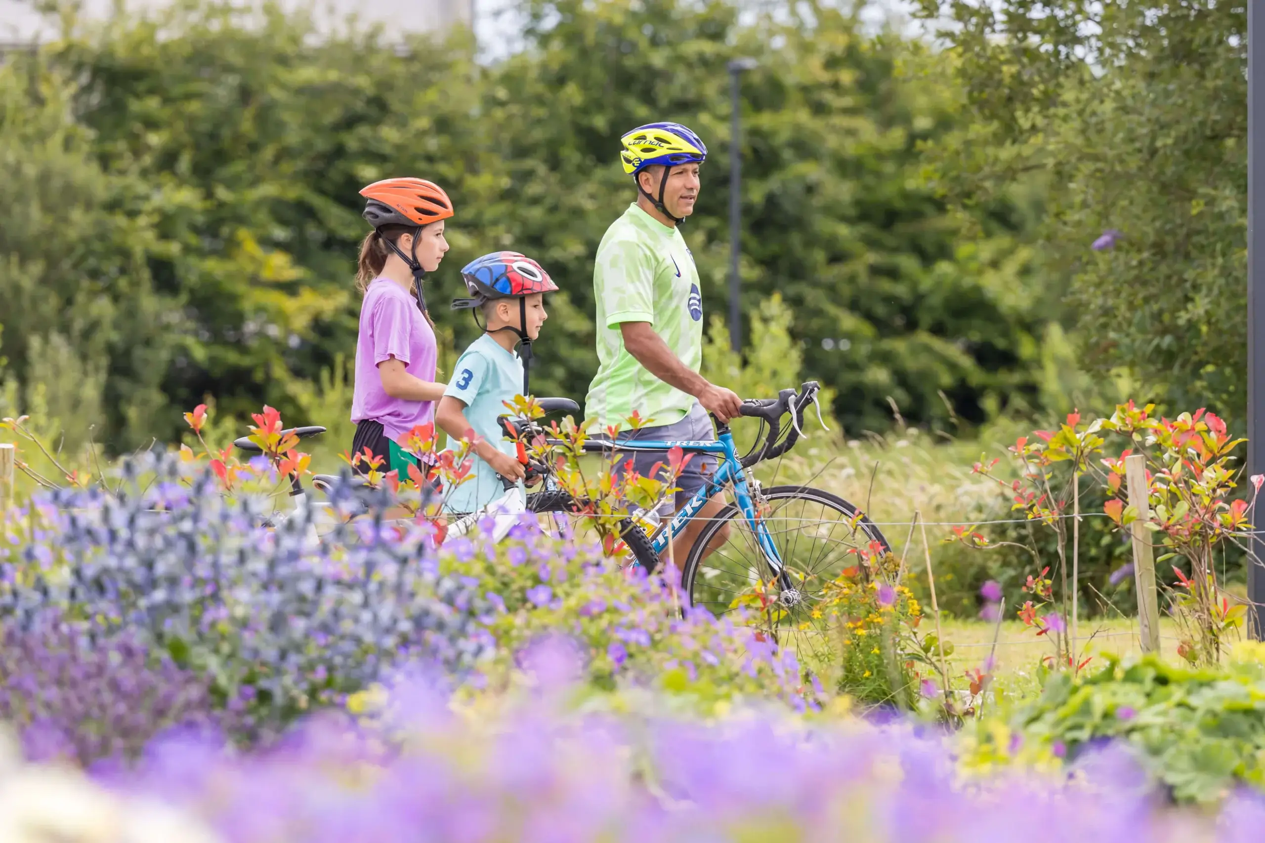 Family cycling through vibrant garden pathway.