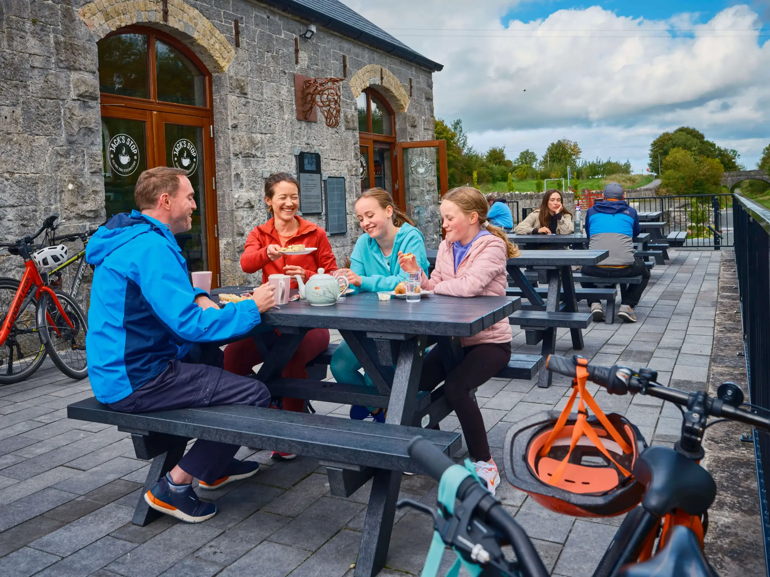 Family enjoying lunch outdoors at a charming stone cafe.