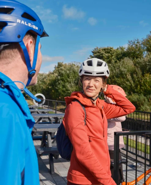 Couple in helmets, preparing for a scenic bike ride near a hotel patio.