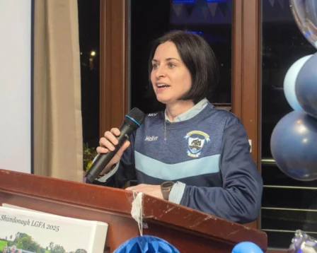 Woman speaking at podium during hospitality event with decorations.