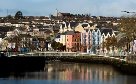 Scenic riverside with colourful buildings and family strolling on bridge in charming town.