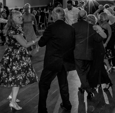 A joyful group dancing at an elegant evening event in a warm, inviting ballroom setting.