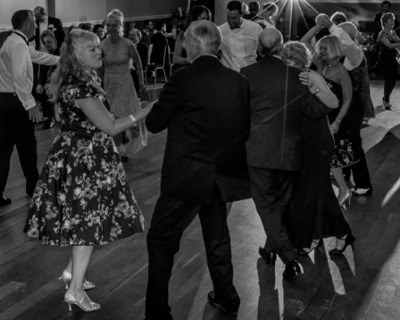 A joyful group dancing at an elegant evening event in a warm, inviting ballroom setting.