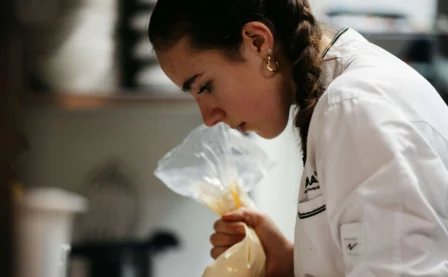 Pastry chef decorating desserts in a warm, inviting hotel kitchen.