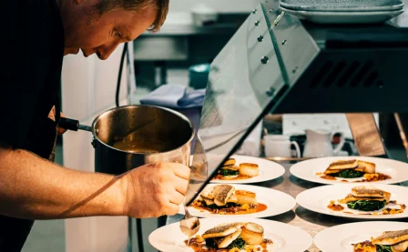 Chef plating gourmet dishes in a warm, inviting kitchen setting.