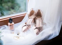 Elegant bridal shoes and jewellery by a window with soft tulle, creating a romantic atmosphere.