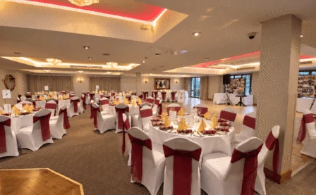 Elegant banquet hall set for a festive celebration with round tables and red accents.