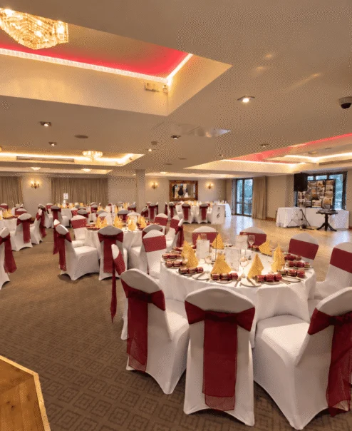 Elegant banquet hall set for a festive celebration with round tables and red accents.