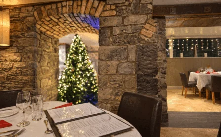 Festive dining area in a rustic restaurant with a beautifully decorated Christmas tree.