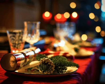 Festive table setting with Christmas crackers, glasses, and seasonal decor in a cosy restaurant.