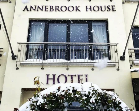 A welcoming hotel entrance with snow-dusted foliage, creating a cosy, festive atmosphere.