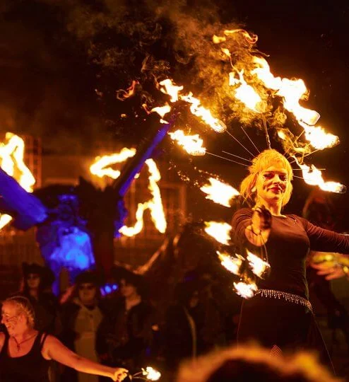 Family enjoying an evening fire performance at a hotel festival, performers twirling flaming props